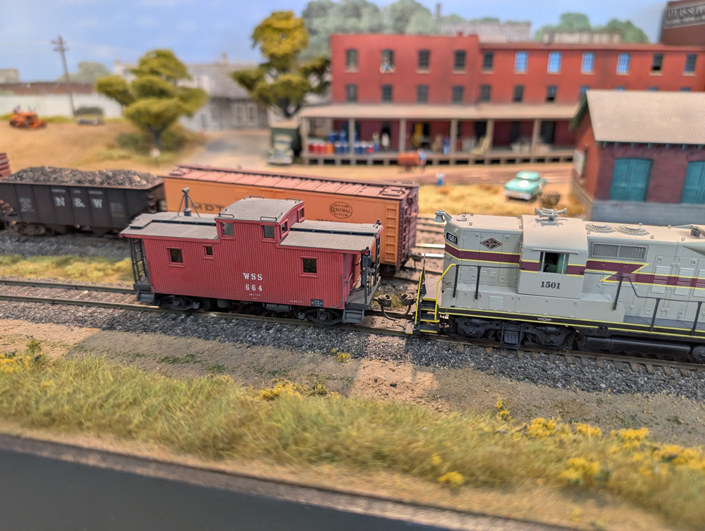 An HO scale GP7 shoving a caboose around a train