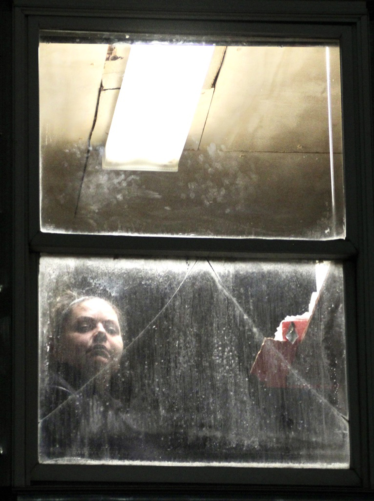 Woman looking through dirty window