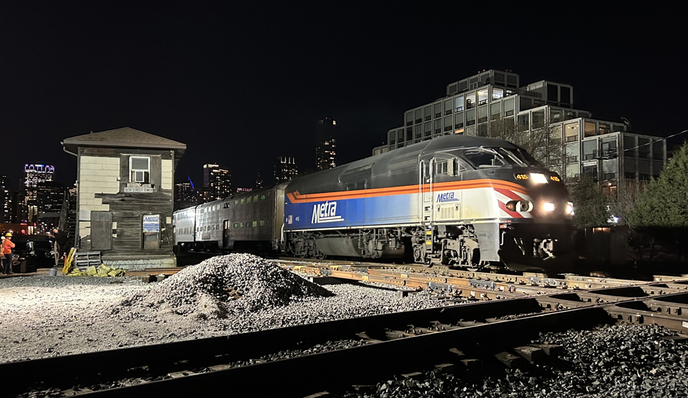 Commuter train passes interlocking tower at night