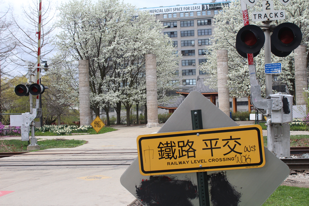Yellow sign with Chinese characters and small lettering in English reading "Railway Level Crossing"