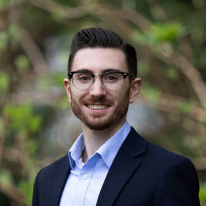Portrait of man in coat and open-collar shirt in outdoor setting