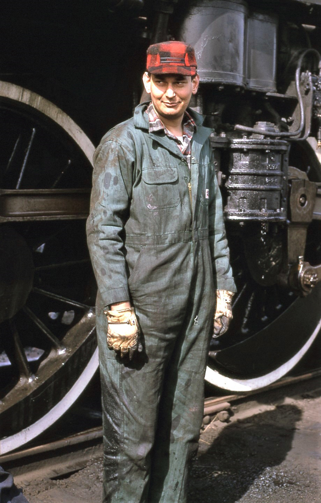 Man in coveralls next to steam locomotive