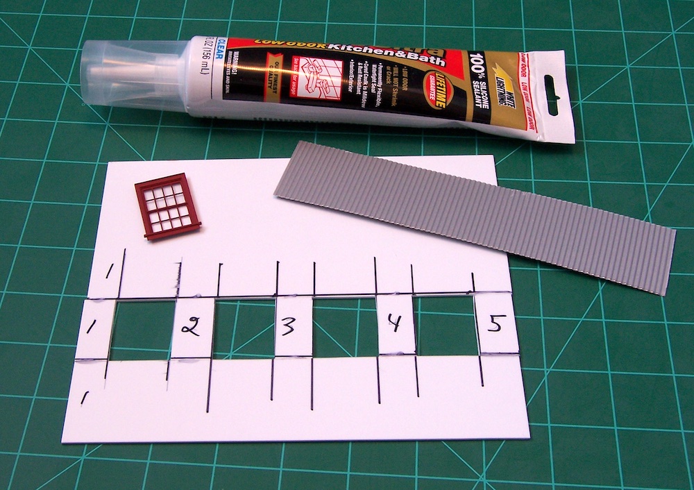 piece of model siding, adhesive, window on cutting board