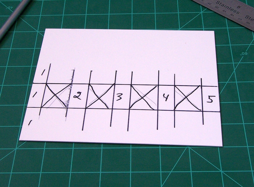 piece of styrene on cutting board with numbers and Xs