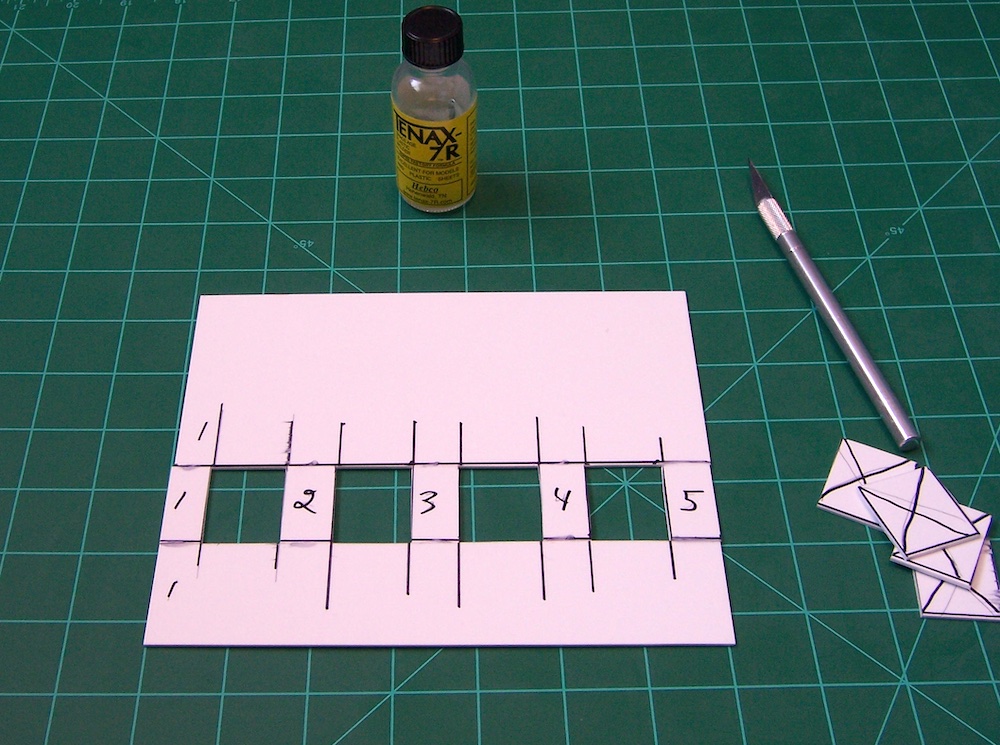 piece of styrene on cutting board with windows cut out