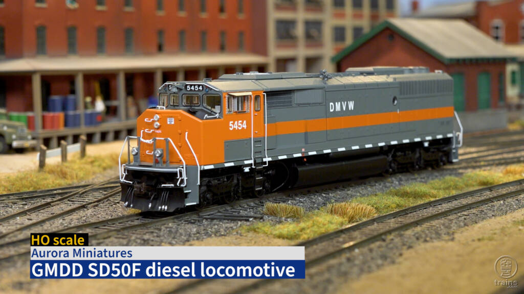 Title screen of product review video showing HO scale diesel in orange and gray paint on scenicked model railroad with title bar in lower left corner.