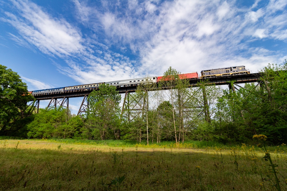 Diesel excursion train travels over bridge.