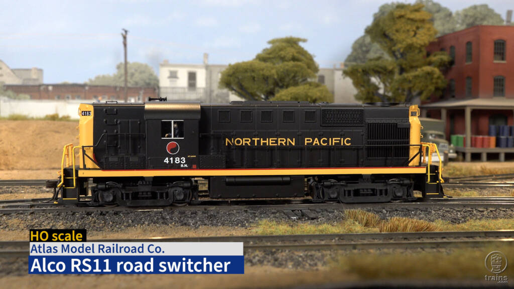 HO scale diesel painted black and yellow on scenicked model railroad with video title bar in lower left corner.