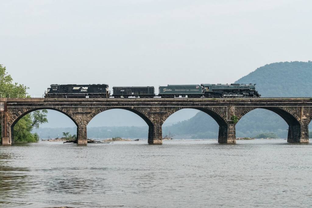Steam locomotive being pulled by diesel on bridge