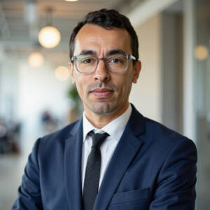 Head shot of man in suit with office in background