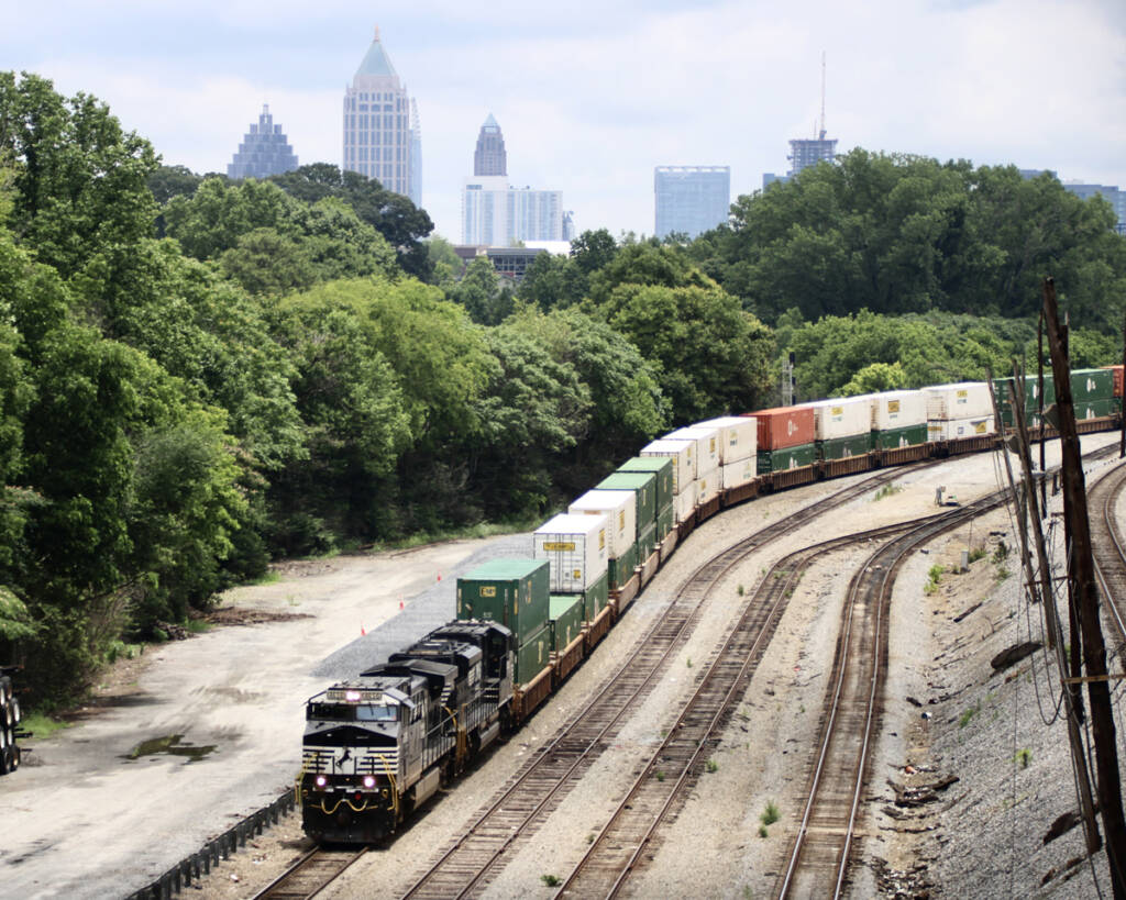 Intermodal train entering yard with skyscrapers in distance