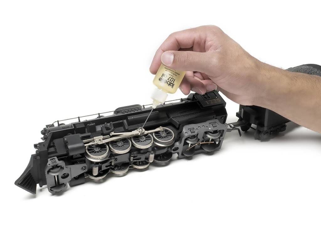 hand holding oil next to model train