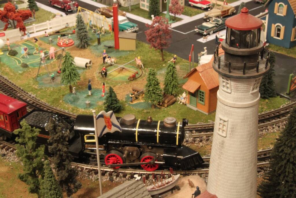 tinplate toy train on curve near model lighthouse