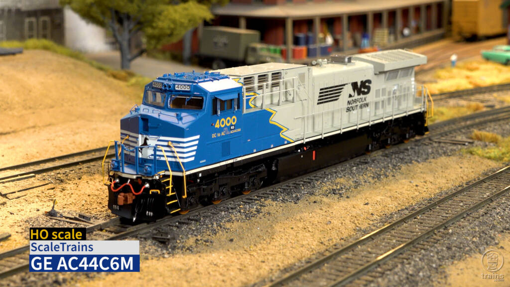 Color photo of HO scale diesel locomotive painted blue, yellow, and gray with black trucks and fuel tank on scenicked HO scale layout. Title for video is shown in lower left corner.