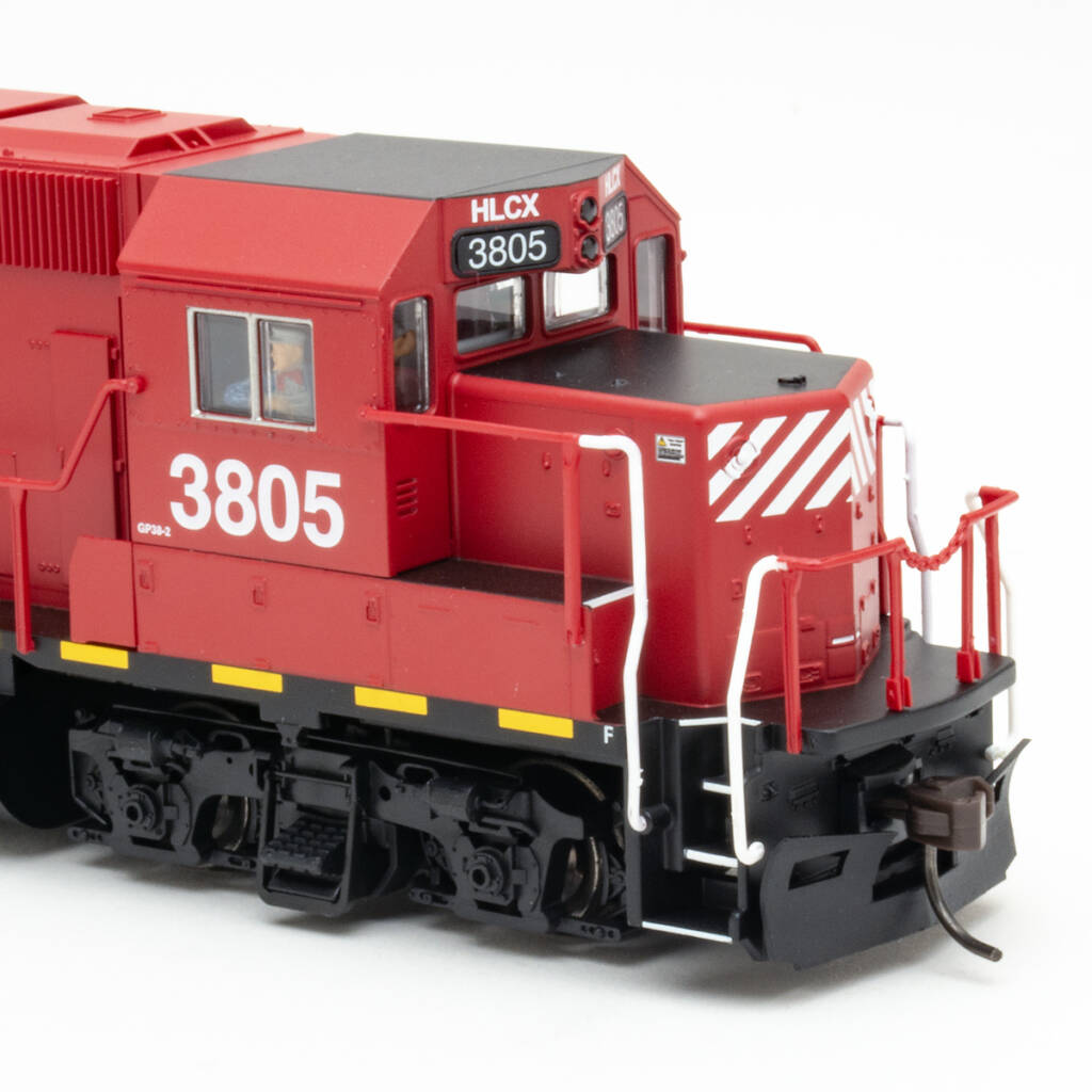 Color photo showing cab and short hood of HO scale EMD hood unit painted crimson and black with white graphics and yellow and white stripes on white background.
