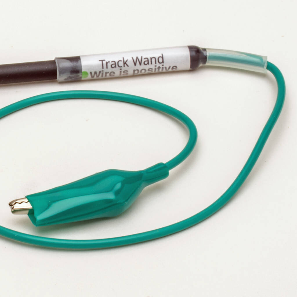Color photo of black-and-white wand with green wire attached to end with alligator clip at opposite end of wire