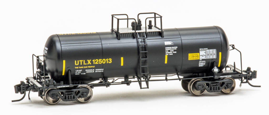 Color photo of N scale tank car painted black with yellow and white graphics on white background.