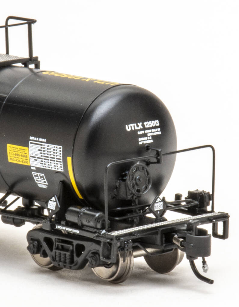 Color photo showing brake end of N scale tank car painted black with yellow and white graphics on white background.