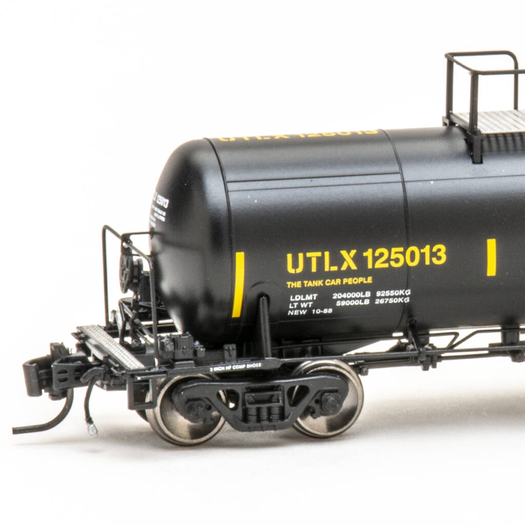 Color photo showing brake end of N scale tank car painted black with yellow and white graphics on white background.