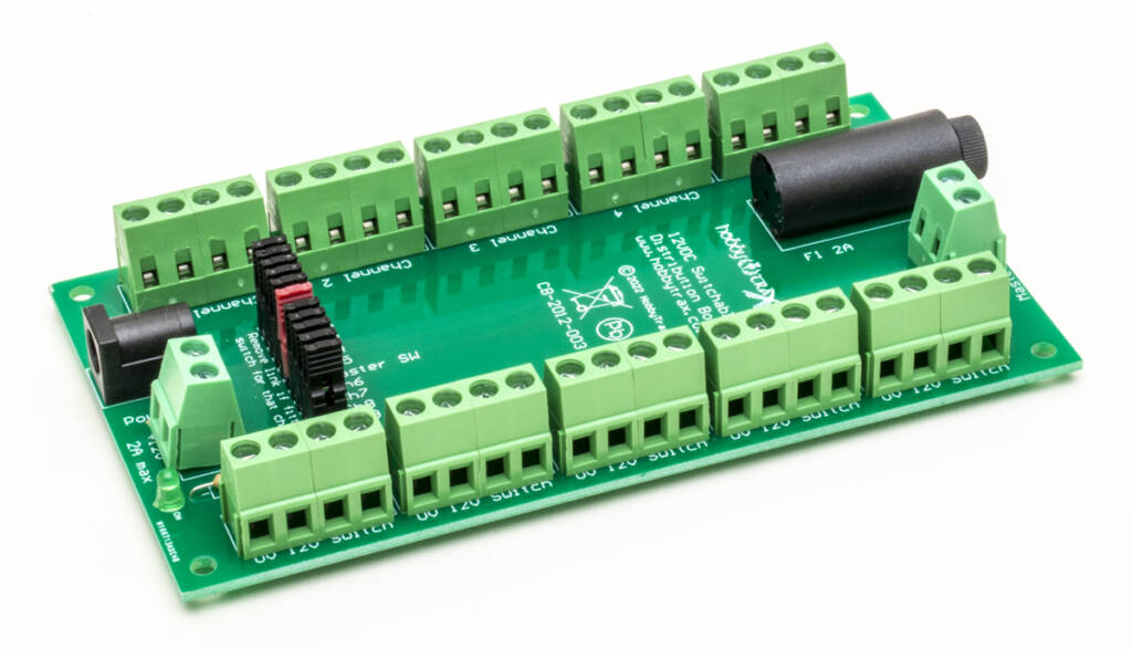 Color photo of green printed-circuit board with screw terminals, plugs, and white printing on white background
