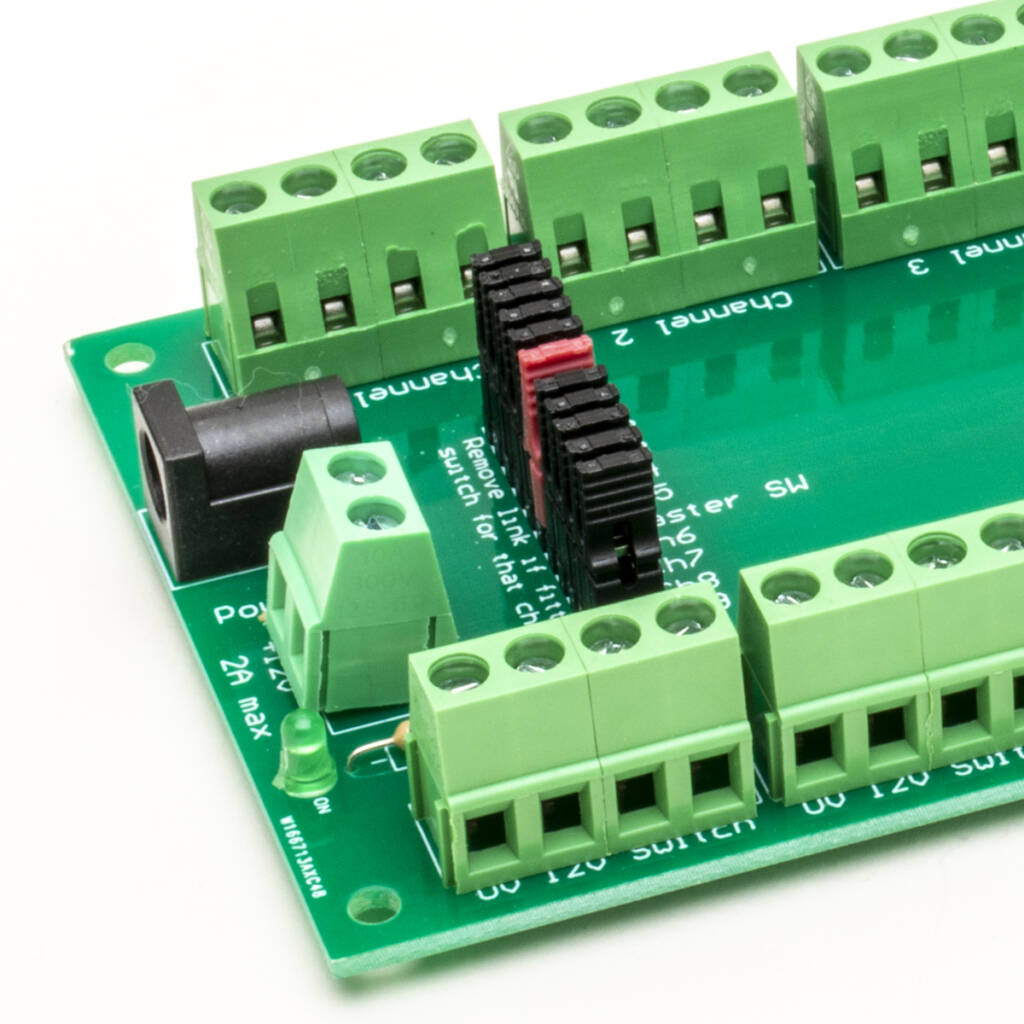 Color photo of green printed-circuit board with screw terminals, plugs, and white printing on white background