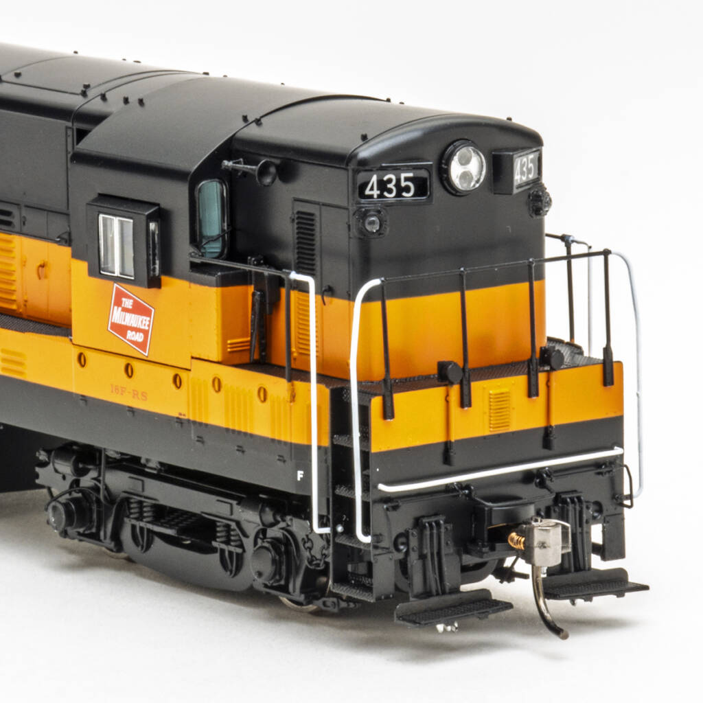 Color photo showing front of HO scale diesel painted orange and black on white background.