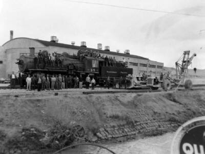 Black steam locomtive with people posing for photograph.