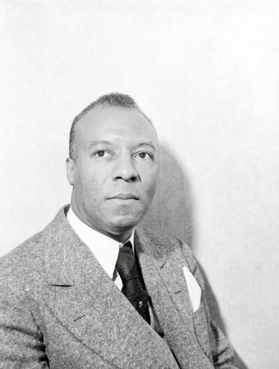 A black and white studio portrait of a man dressed in suit and tie