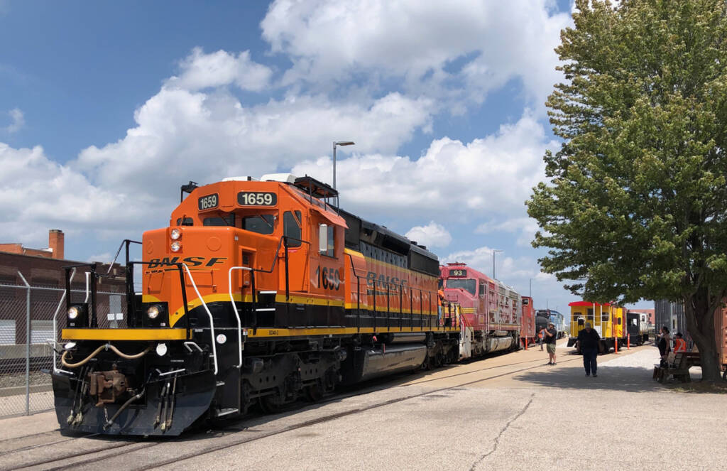 Orange and black locomotive pulling weathered silver and red diesel