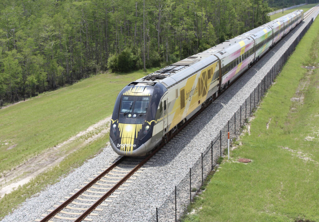 Passenger train with yellow and white locomotive on single-track main line