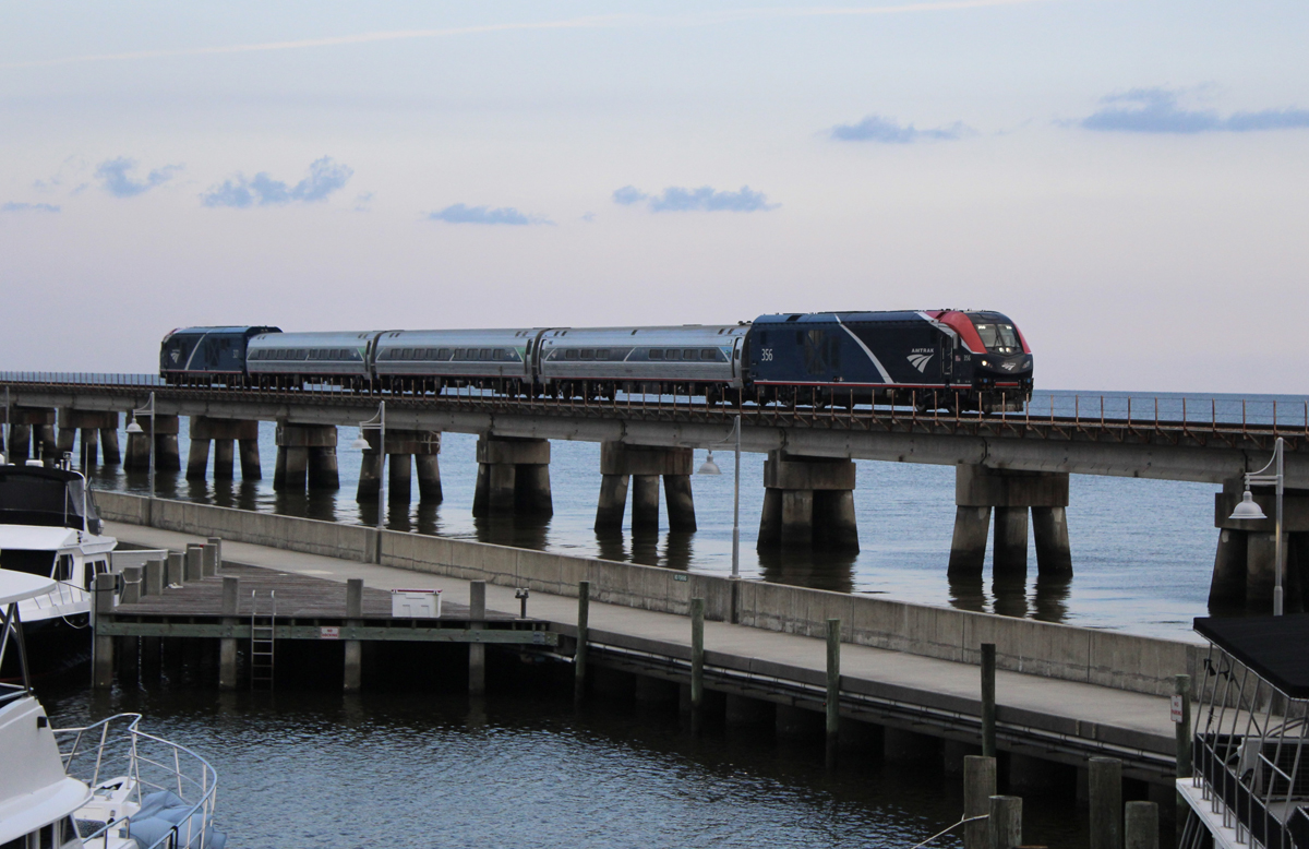 Passenger train crosses bridge in evening light, Aug. 18, 2025