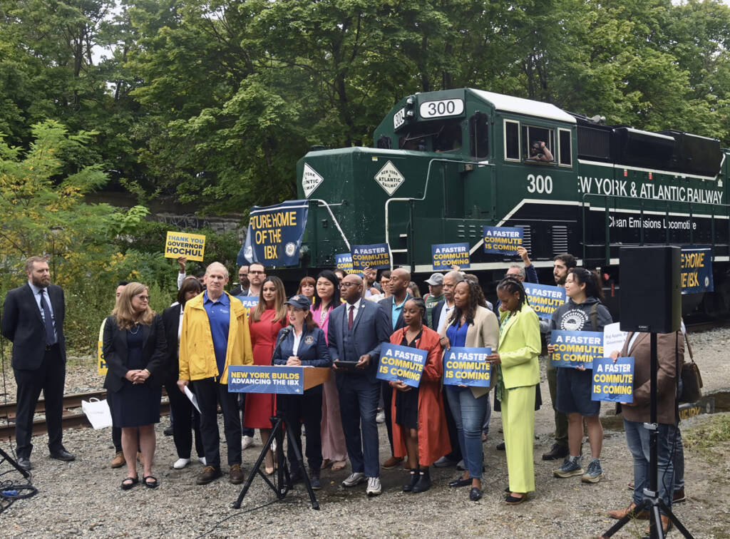 Group of people standing in front of locomotive to make announcement
