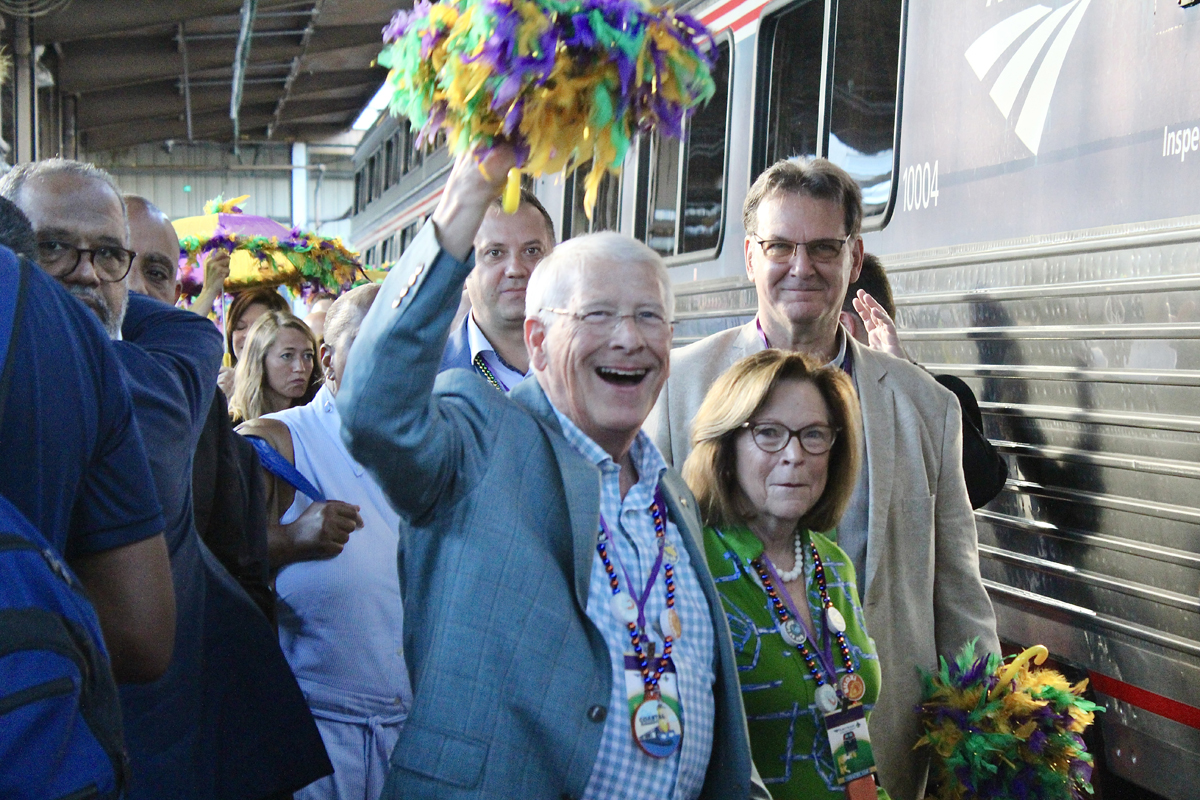 Man waving multi-colored pom-poms on train platform