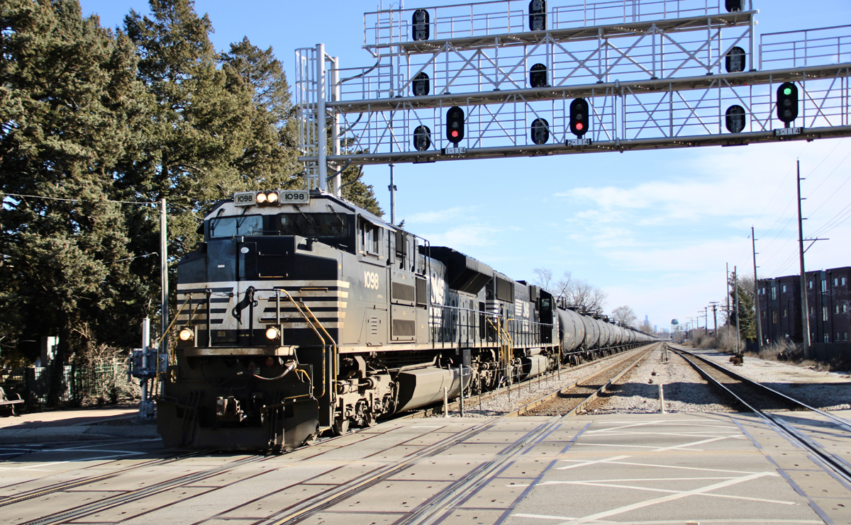 Black locomotives on train passing under signal bridge