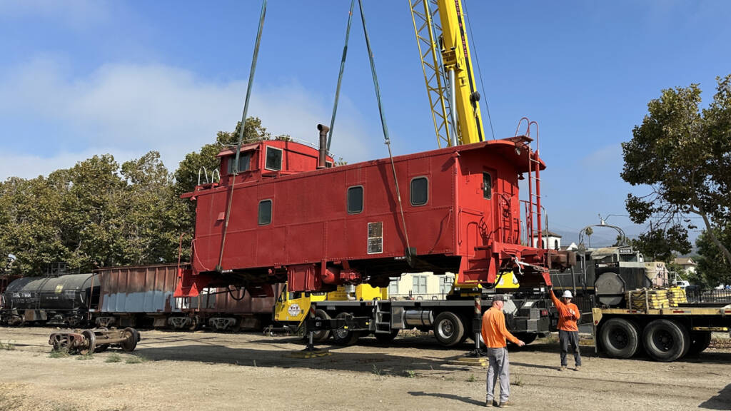 Crane lifting red caboose