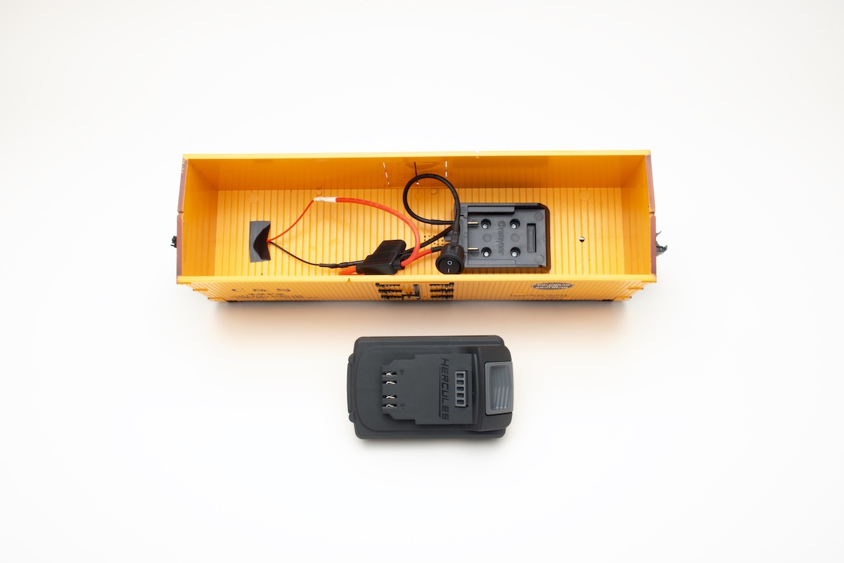 Inside of a large scale boxcar with a battery next to it.