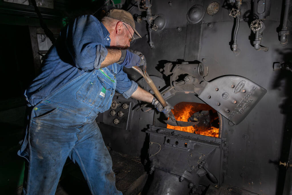 Fireman shoveling coal into firebox of steam locomotive