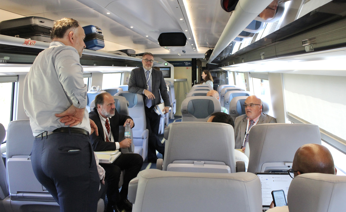Man standing in Acela car, talking with other people