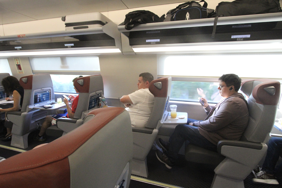 Interior of Acela first class car showing larger windows and open luggage racks