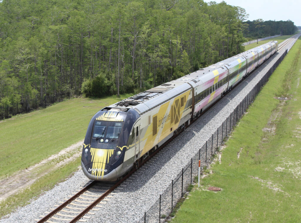 View from bridge of white and yellow locomotive and passenger train