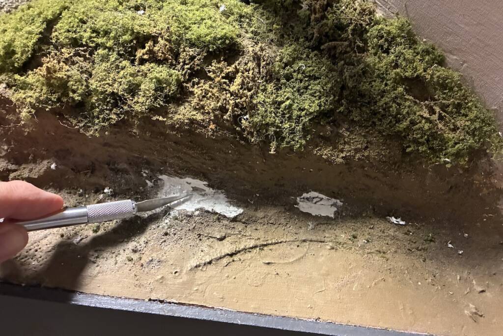 hand holding hobby knife near layout