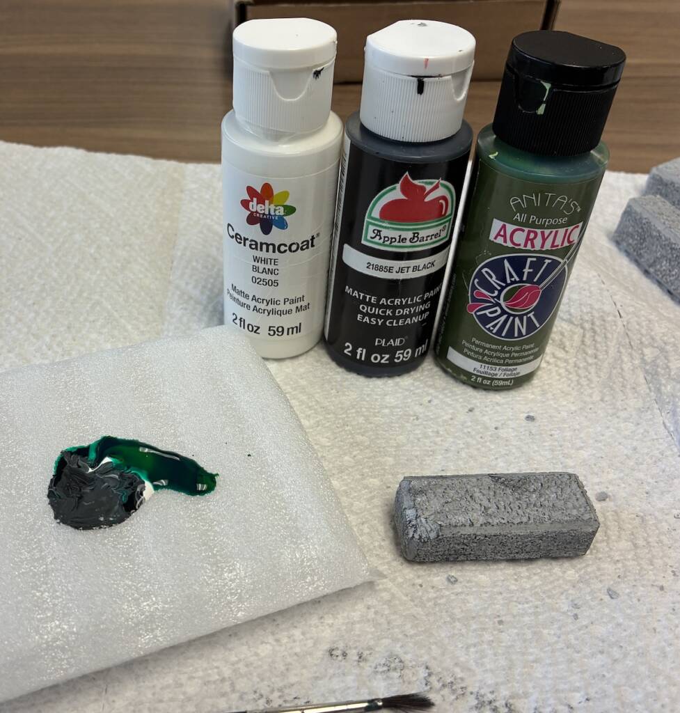 three colors of paint, a pile of mixed paint, a paintbrush, and a block