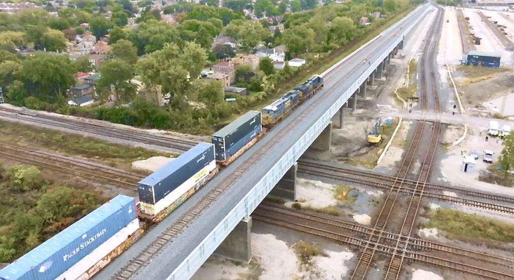 Aerial view of intermodal train on rail bridge, with two diamond crossings visible at ground level