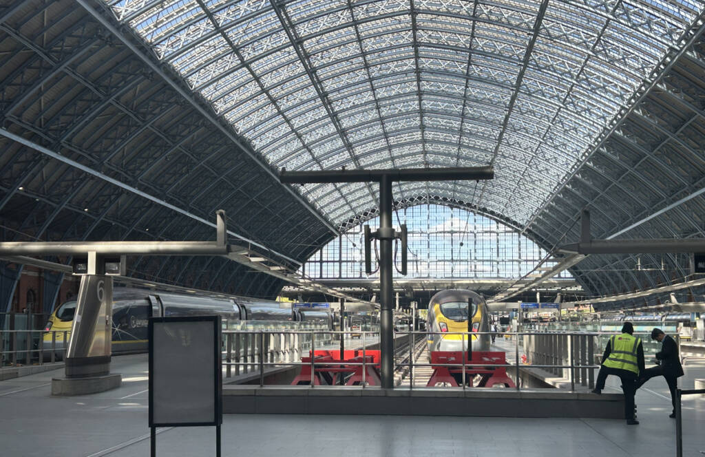 Trains in station with large arch roof over platforms