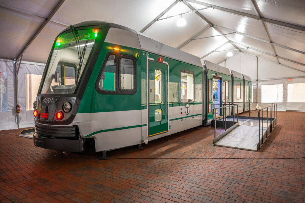 Mockup of green and white light rail vehicle inside of tent