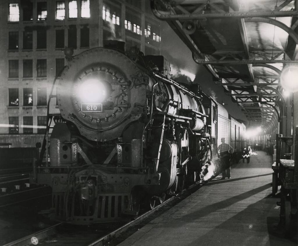 Steam-powered passenger train waiting at a station at night