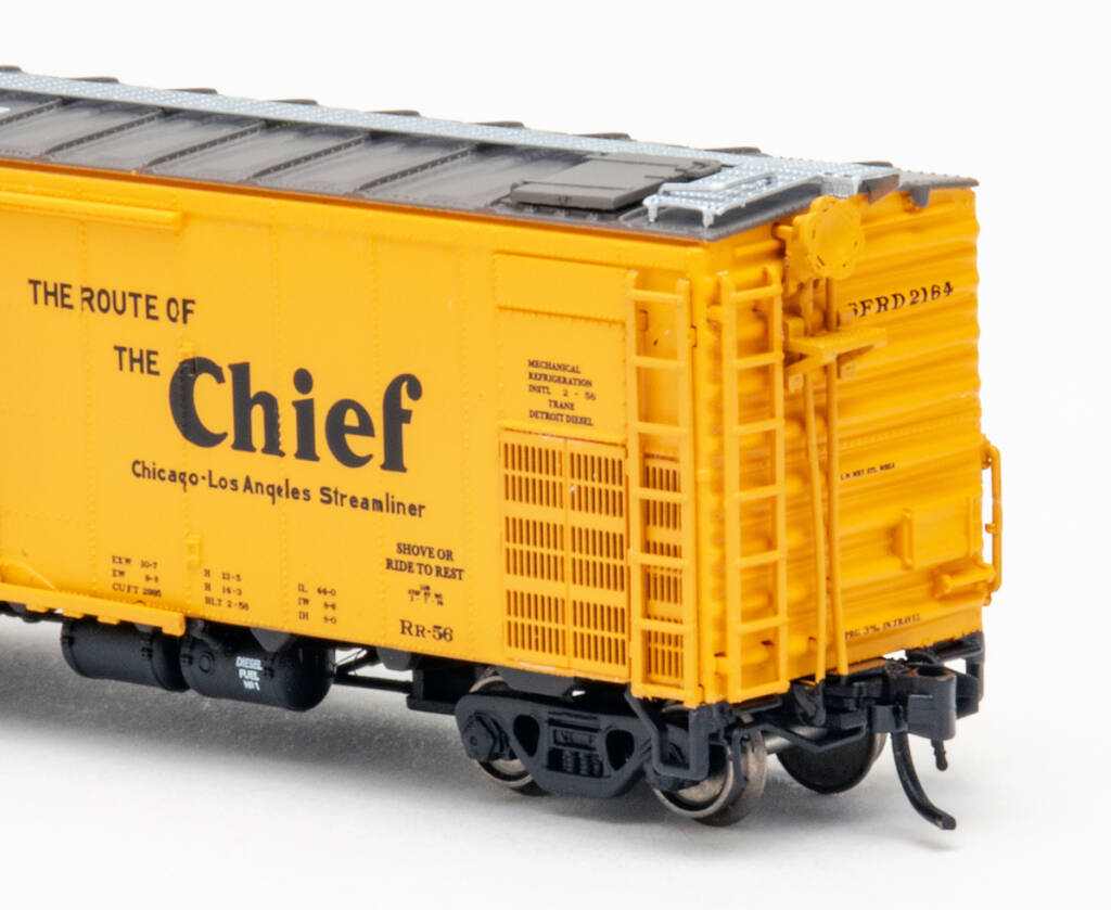 Color photo showing brake end of steel refrigerator car painted yellow with brown roof and black underbody on white background.
