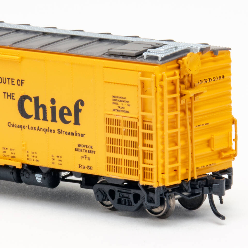 Color photo showing brake end of steel refrigerator car painted yellow with brown roof and black underbody on white background.