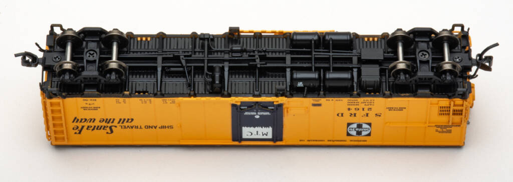 Color photo showing underbody of N scale steel refrigerator car painted yellow with blue door and black underbody on white background.