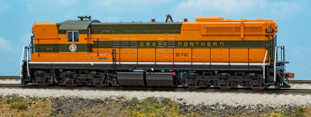 Color photo of HO scale six-axle EMD hood unit painted orange, green, and yellow with red, white, and black graphics on scenicked base with a sky blue background. 